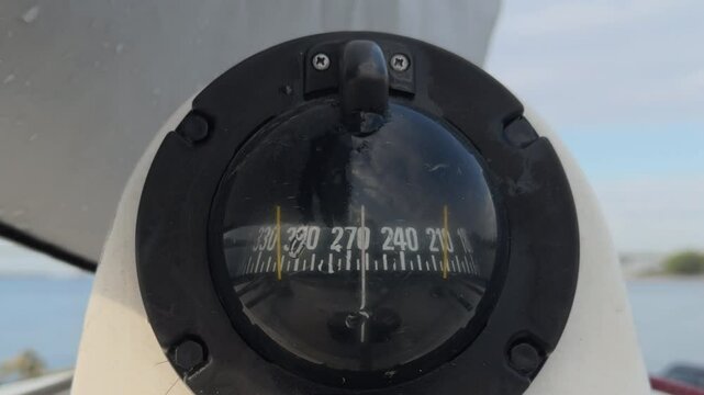 A gyroscope on a boat in close-up on a sunny day while sailing. A close-up of the black compass of the navigation device with which the ship's course is determined. White yacht with navigation