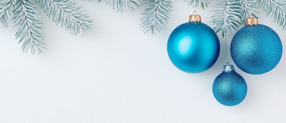 blue Christmas ornaments hanging from frosted pine branches on a white background. Minimalist holiday scene