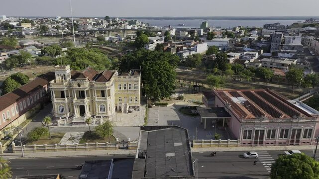 Drone flies to the left in front of Palacio Rio Negro and then orbits around Parque Senador Jefferson Peres in Manaus, Amazonas, Brazil