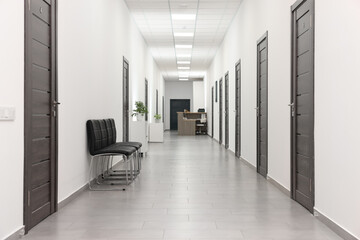 Empty hospital corridor with chairs and doors