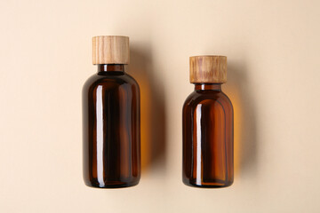 Essential oils in bottles on beige background, top view