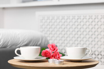 Burning candles, two cups of drink and flowers on coffee table indoors. Space for text