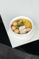 Vertical Shot of  Yellow Noodles with Meatballs and Red Pork: A Flavorful Breakfast Bowl for Hotel Dining