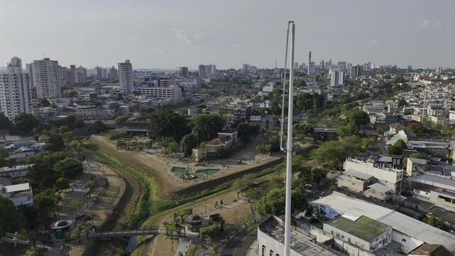 Drone lowers from high view of park to in front of iron arcs at the southern entrance to Parque Senador Jefferson Peres in Manaus, Amazonas, Brazil
