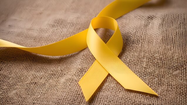 Yellow ribbon on textile background with copy space for endometriosis awareness month or sign for microencephaly and suicide prevention