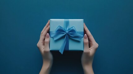 A pair of hands holding a beautifully wrapped blue gift box with a ribbon.