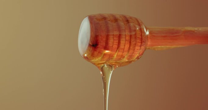 Honey, drip and stick in studio for nutrition, antioxidants and natural sugar. Raw, organic sweetener and drizzling on brown background for healthy food, antibacterial properties and gut health