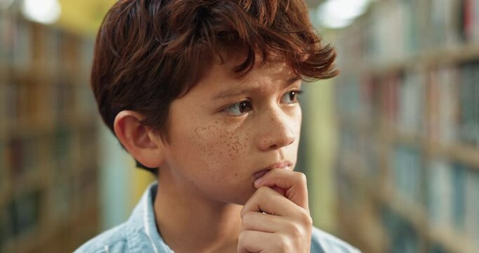 Boy, thinking and library with book shelf for choice, decision or selection of novel, story or information. Young male person or teenager in wonder or thought for knowledge, education or learning