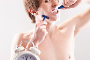 Young man hurriedly multitasks morning hygiene routine