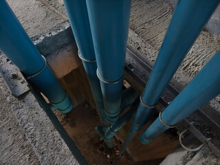 A bright blue pipes attached to a solid concrete wall