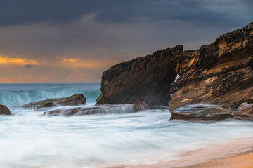 Sunrise at the seaside with rocks and beautiful diffused light by the rain clouds