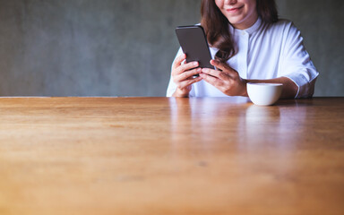 Closeup image of a young woman holding and using mobile phone