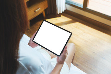 Top view mockup image of a woman holding digital tablet with blank desktop screen on the bed