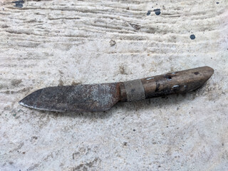 The old knife, once sharp and gleaming, now shows the marks of time with a blade covered in rust. Its weathered surface tells stories of countless uses, the handle worn smooth from years of grip.