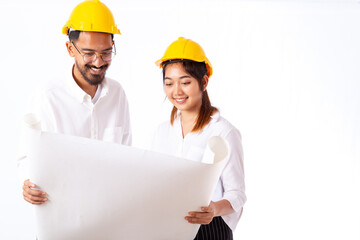 Young engineer and architect holding and working together on building site blueprint at construction site or factory.	