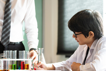 Young Asian Schoolboy studying chemistry in the classroom with teacher. He helping his student to prepare for new exam.