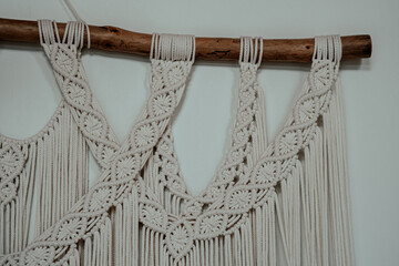 Crafting intricate macramé wall hangings with natural fibers for home decor in a cozy indoor...