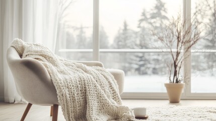 A white chair with a white blanket draped over it sits in front of a window