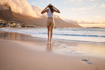 Woman, walking and beach with back for holiday or travel adventure by ocean for fun, peace and relax. Female person, calm and vacation on weekend as carefree for freedom, nature and outdoor in summer