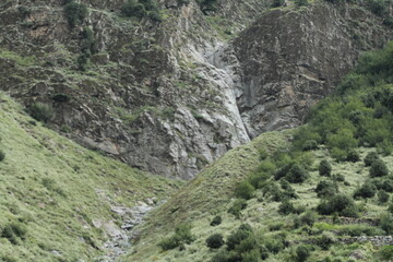 A rugged black stone formation on a barren mountainside, devoid of trees or vegetation.