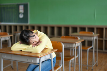 教室の机に寝そべる女の子