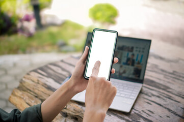 Male hand holding smartphone with blank screen at the outdoor space. Hand holding smartphone and touching white blank screen mockup. 