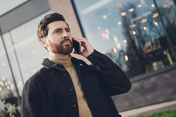 Photo of young successful man walking city street autumn day talking modern device outside