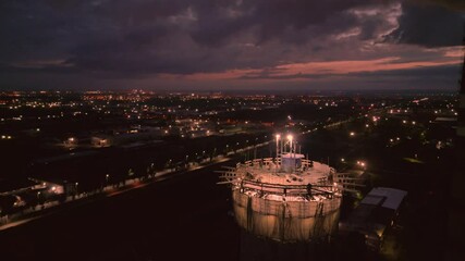 Illuminated construction site at dusk.Dangerous work at the nighttime.Workers build a tall chimney for a plant.Construction process.Contractor renovation is smokestack on highrise.Worker in hardhat 
