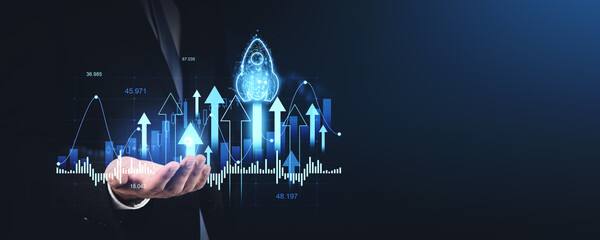 Businessman holding holographic financial graphs and rocket representing growth and success concept.