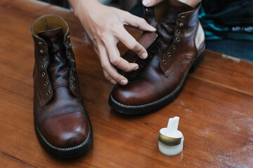 Close up of a hands polishing a leather boots with brush, on wooden table, shoes shining and cleaning.