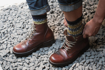 Man is putting on a pair of brown full grain leather shoes boots at outdoor with stone floor, Trying shoes leather boots.