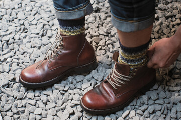 Man is putting on a pair of brown full grain leather shoes boots at outdoor with stone floor, Trying shoes leather boots.