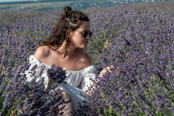 Beautiful woman at purple lavender field with violet blossom lavanda flowers. French young blond girl in provence lavender farm wears white dress.	