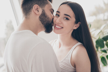 Photo of attractive trendy cheerful married young couple spending free time kiss cheek move new apartment home interior indoors