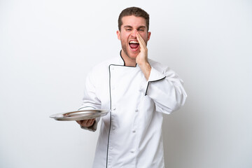 Young caucasian chef with tray isolated on white background shouting with mouth wide open