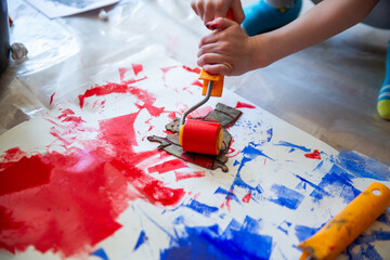 Children creating lino cut prints on paper using rollers, paint, and spoons in an art workshop. Creativity, craft techniques, and artistic expression, educational and creative stock imagery.