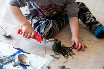 Children creating lino cut prints on paper using rollers, paint, and spoons in an art workshop. Creativity, craft techniques, and artistic expression, educational and creative stock imagery.
