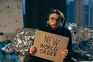 Conspiracy theory concept. A man holds a sign with a pseudoscientific slogan.