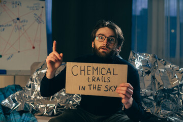 Conspiracy theory concept. A man holds a sign with a pseudoscientific slogan.