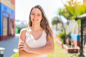 Young pretty woman at outdoors keeping the arms crossed in frontal position