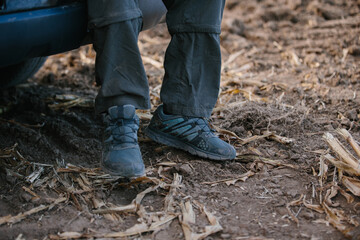 Fototapeta premium Man's legs on the background of a plowed corn field.