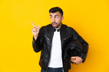 Caucasian man with a motorcycle helmet over isolated yellow background intending to realizes the solution while lifting a finger up