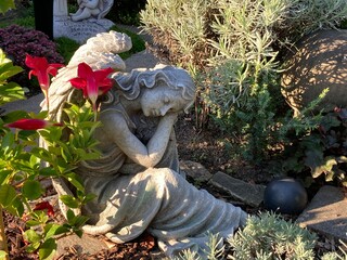 Engel auf dem Friedhof mit roten Blumen in der Natur