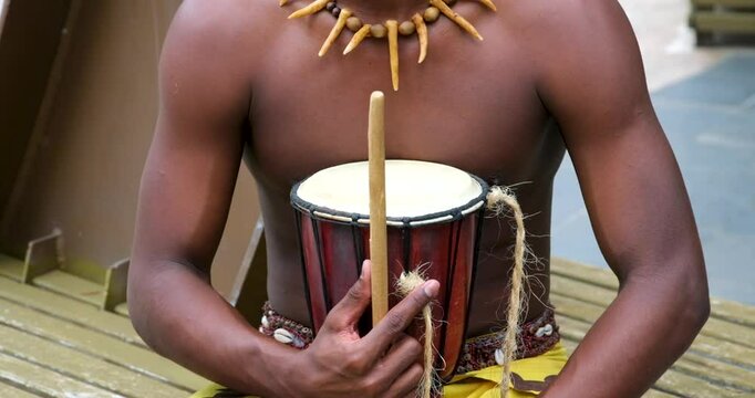 Papuan with a drum strong hands of a tanned dark-skinned man on his neck a necklace of bones in his hands a drum actors performance dancers in their hair feathers