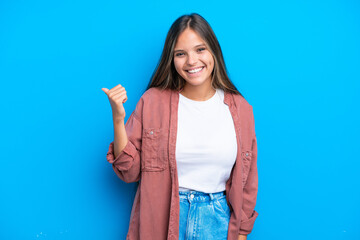 Young caucasian woman isolated on blue background pointing to the side to present a product