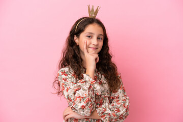 Little caucasian princess with crown isolated on pink background thinking an idea while looking up