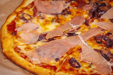 A delicious pizza topped with thin slices of prosciutto, melted cheese, and caramelized onions on a crispy golden crust. The rich colors and textures highlight the mouth-watering ingredients.