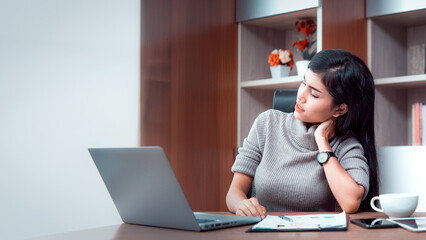 Stressed young Asian businesswoman have neck aches and pains while working in office, work hard and office syndrome concept.