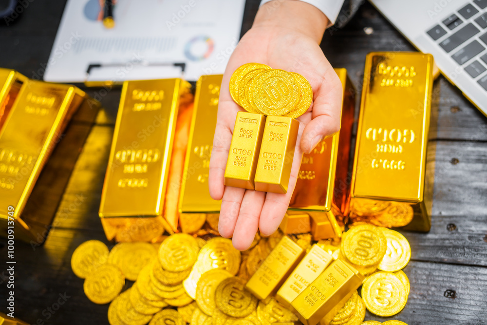 Wall mural businessman in suit sits at his desk, holding a shining gold bar. financial charts, the scene symbol