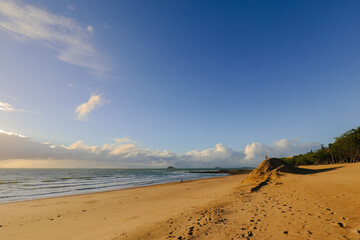 Children playing on large mound of sand on the beach